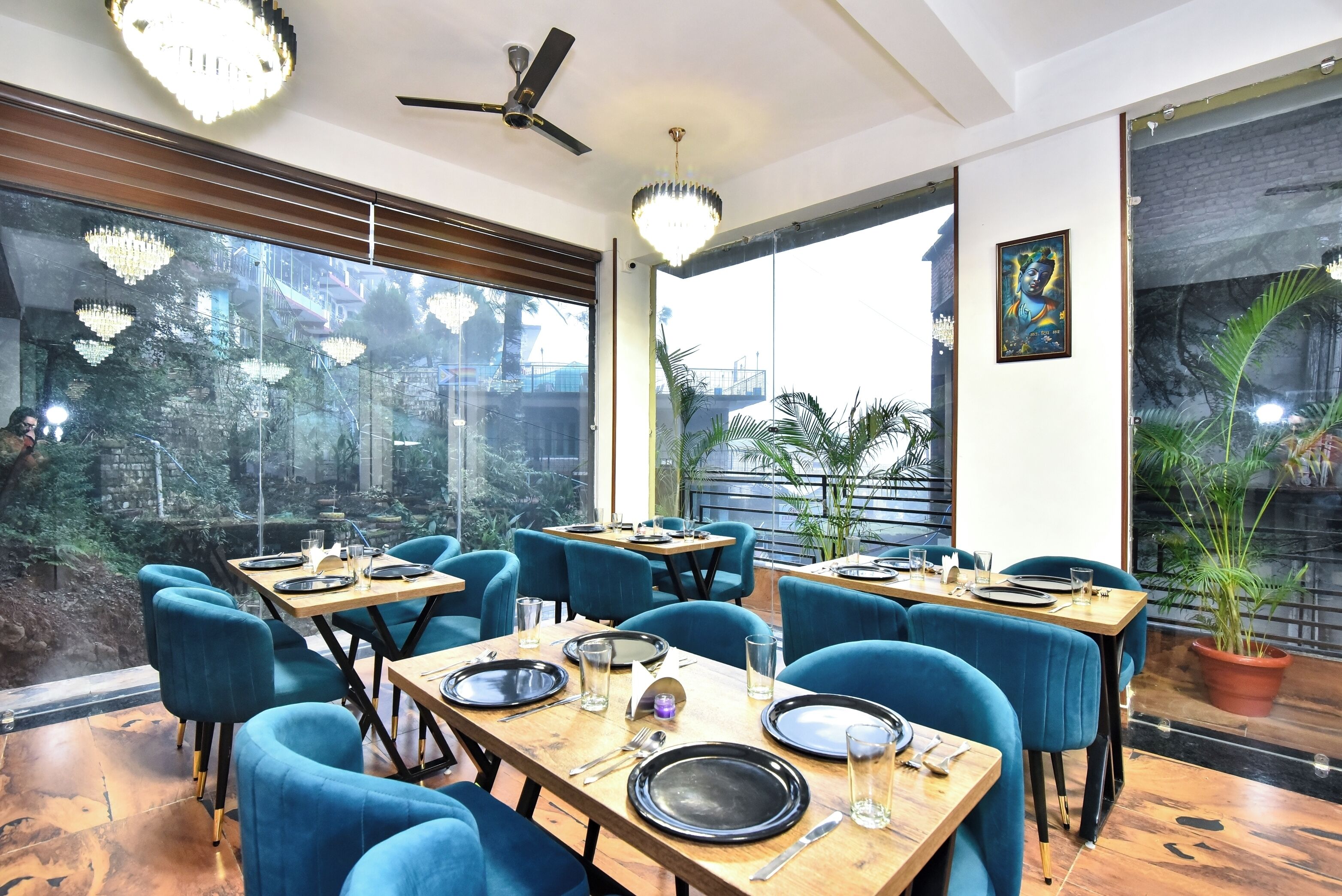Un restaurant avec des tables en bois, des chaises bleues et de grandes fenêtres donnant sur l’extérieur.