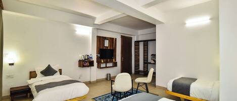A bedroom with two beds, a TV, a small desk, and a chair.