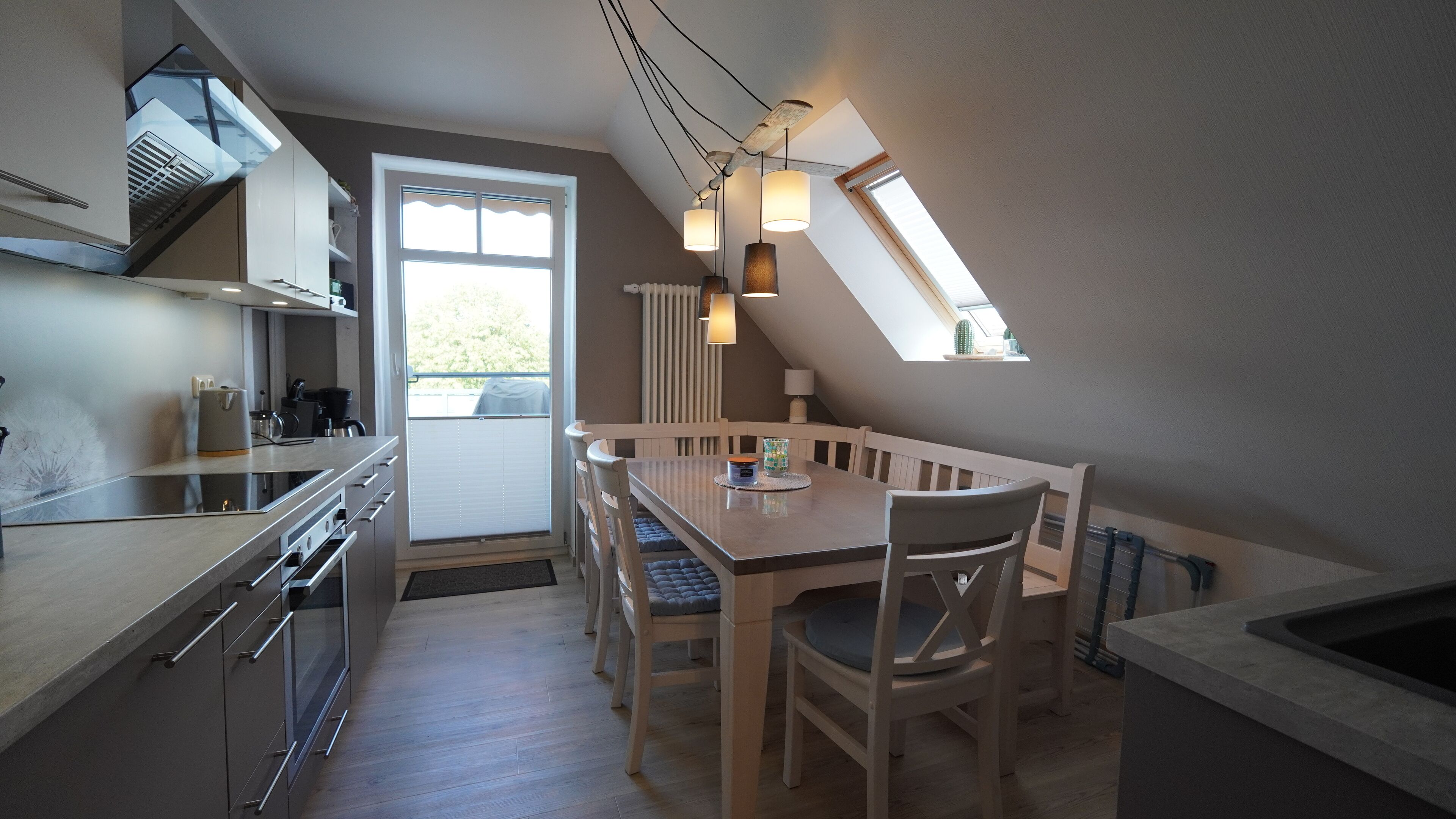 Et moderne køkken med spiseplads, med et stort vindue, ovenlys og en indbygget ovn.