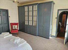 Un dormitorio con una cama, una silla roja y armarios grises.