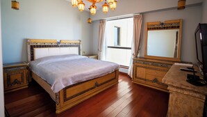 Een slaapkamer met een groot bed, een houten hoofdbord, een kroonluchter, een kaptafel en een grote spiegel.