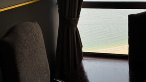 Een kamer met een groot raam, een kunstwerk in een lijst aan de muur en een gestreept fauteuil.