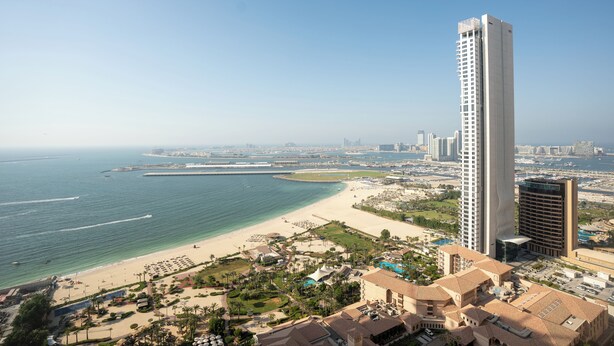 Een hoog hotel met uitzicht op het strand, inclusief een zandstrand en een jachthaven.