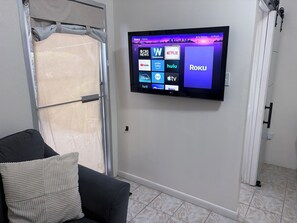 A flat-screen TV mounted on a wall displaying various streaming services. - Cozy Studio In Center of Island • Close to Health City, Beaches and  Restaurants (Bodden Town)