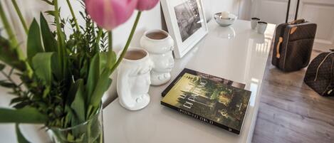 Uma mesa com um livro, uma fotografia emoldurada e um vaso de tulipas cor-de-rosa.