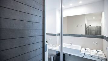 A modern bathroom with a large mirror, white sink, and towel rack.