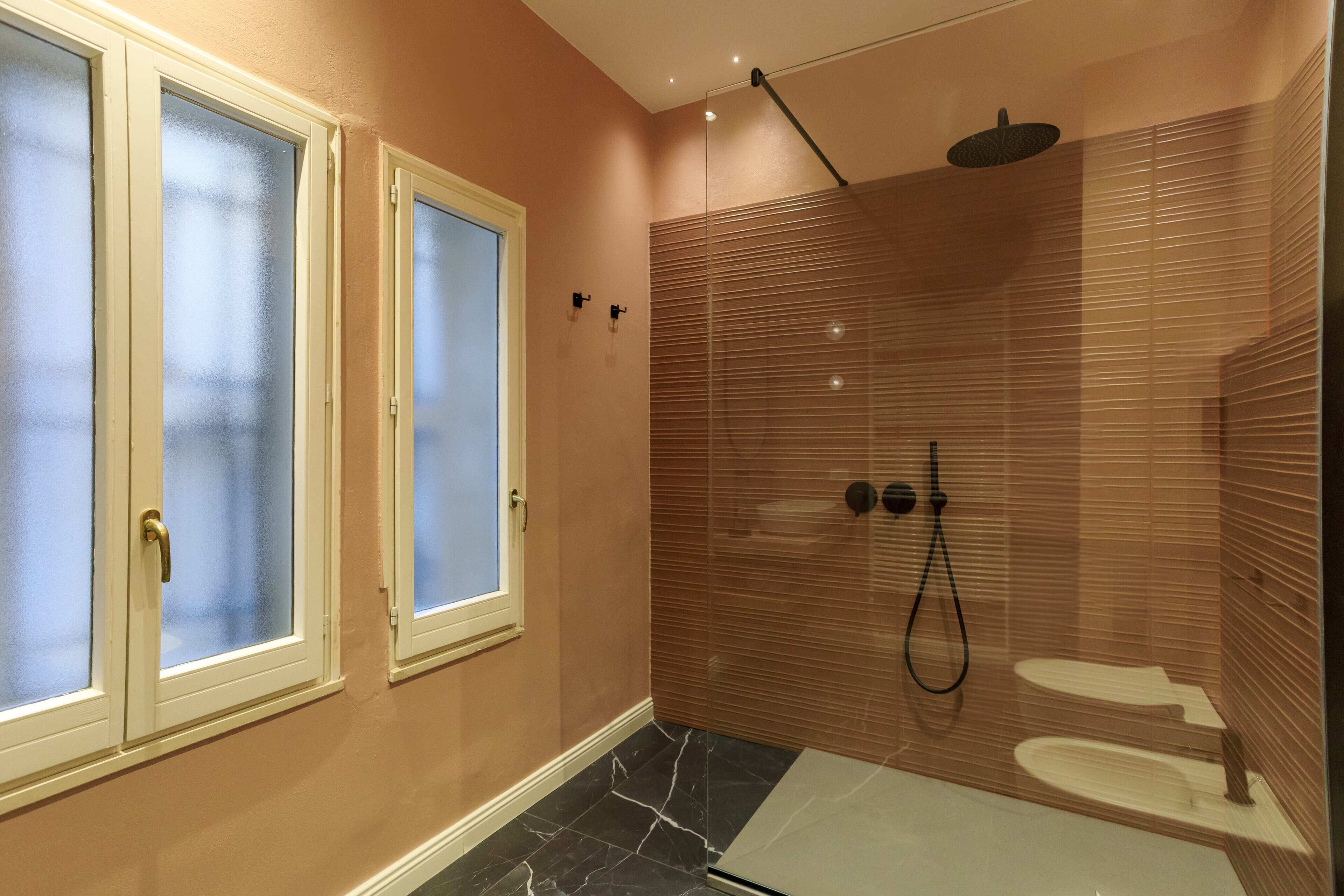 Une salle de bain moderne dotée d’une douche à parois de verre, de toilettes et d’une fenêtre en verre dépoli.