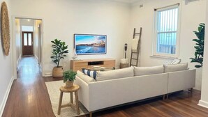 Ein modernes Wohnzimmer mit einer großen Couch, einem Fernseher und Blick aufs Meer.