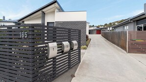 A modern residential building with a gated driveway, numbered mailboxes, and a clear sky. - Residential Retreat, Groups & Families-Sleeps 15 (Warrane)