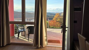 A room with a large sliding glass door leading to an outdoor area with a view of a hilly landscape.