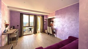 A modern living room with a purple couch, a dining area with a table and chairs, and a view through large windows.