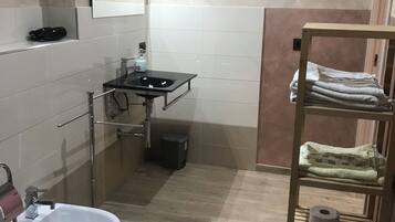 Baño con lavamanos, bidé y repisa con toallas.