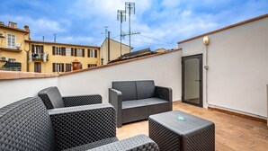 A rooftop patio with wicker furniture, a door, and a view of neighboring buildings. - YiD Donatello con terrazzo (Florence)