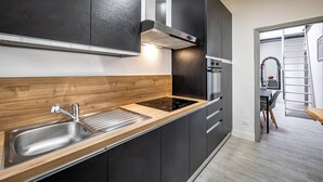 A modern kitchen with a stainless steel sink, wooden countertop, and black cabinets. - YiD Donatello con terrazzo (Florence)