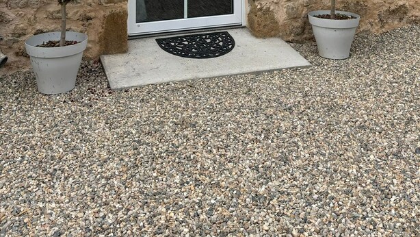 A stone building with a white door and window shutters, two potted plants, and a gravel driveway. - Maison D'hôtes L'atelier Détente et Spa Animaux Acceptés Jacuzzi, Sauna = Option (Caudrot)