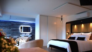 Une chambre d’hôtel moderne équipée d’un lit, d’un coin salon avec une table et d’un téléviseur fixé au mur.
