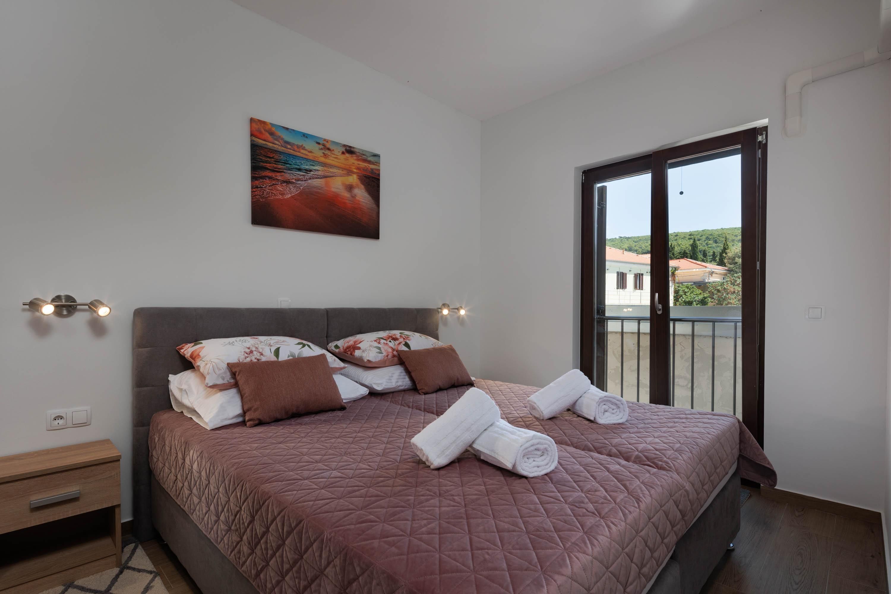 Un dormitorio con una cama grande, un cuadro en la pared y un balcón con vistas.