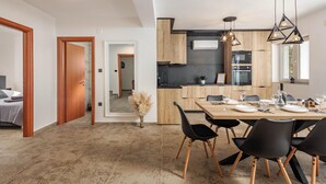 A modern kitchen with wooden cabinets, a black countertop, and a dining area with a wooden table and black chairs. - Pool House Beba Tribalj Lake (Vinodol)