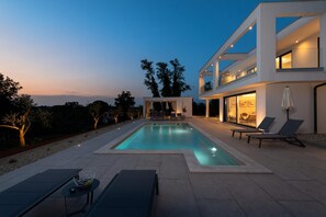 A modern house with a swimming pool, outdoor seating, and a large window overlooking the landscape. - Luxury Villa Sonia With Wellness Gym (Sveta Nedelja)