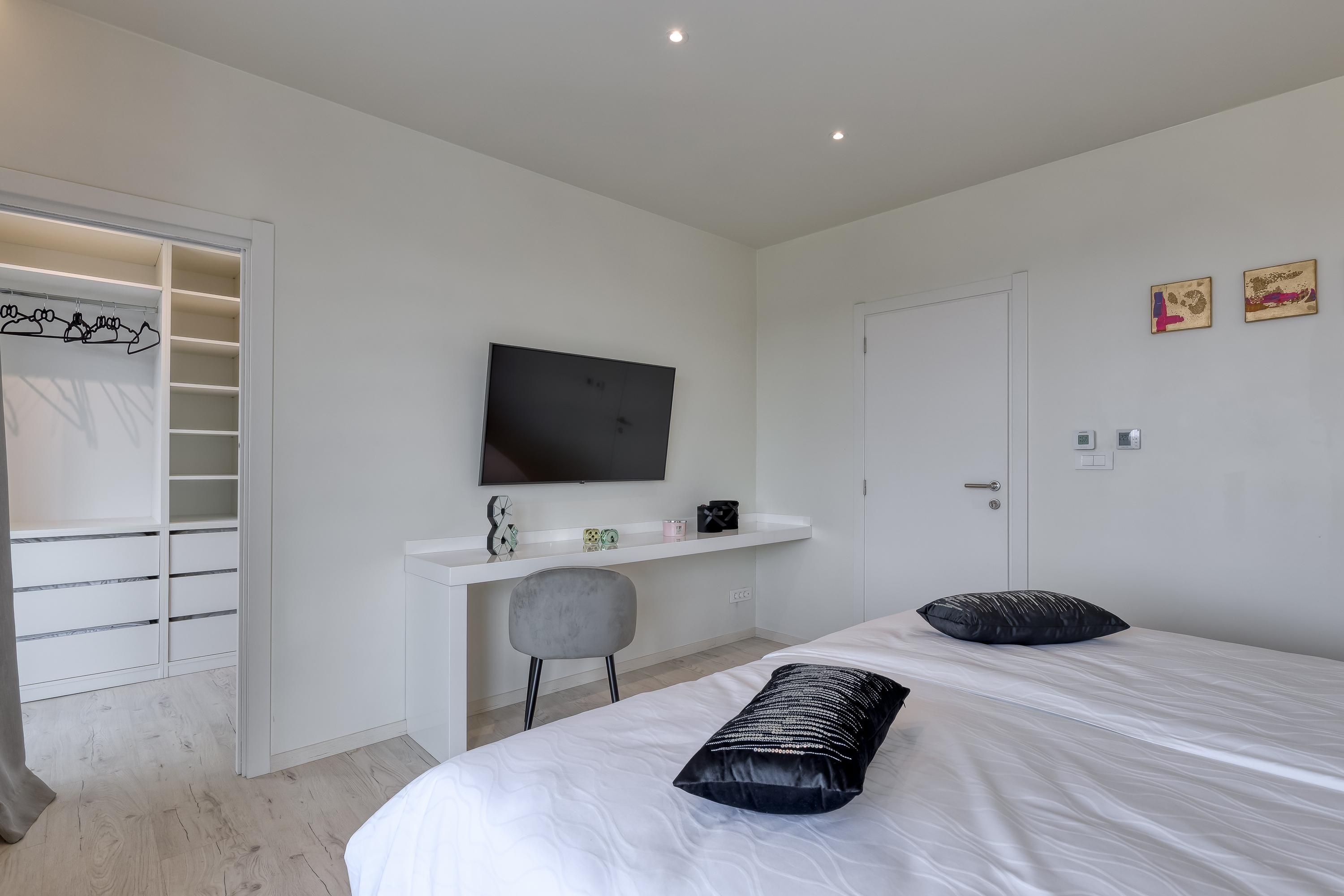 A bedroom with a bed, a desk, a chair, a TV, and a wardrobe.