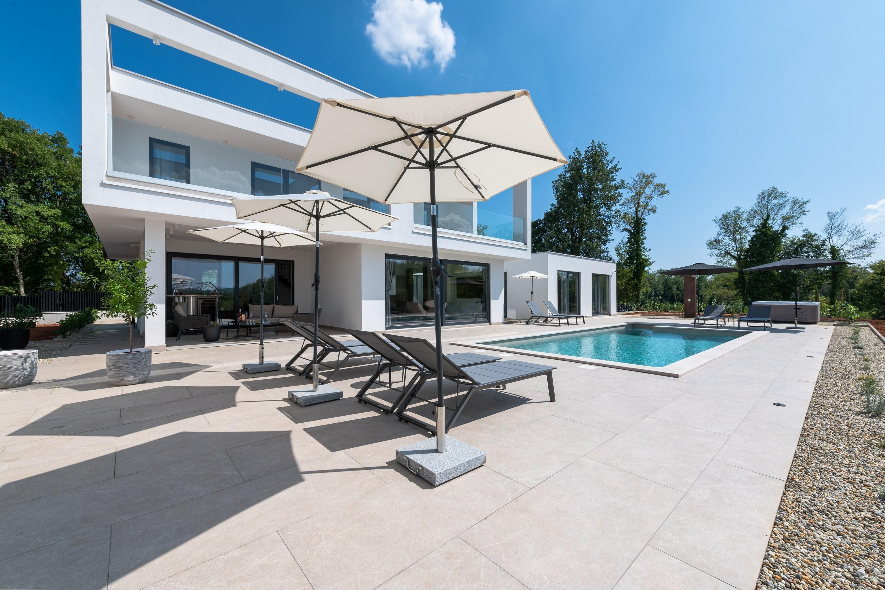 Une maison moderne dotée d’une piscine, d’un espace extérieur aménagé et d’un jardin bien entretenu.