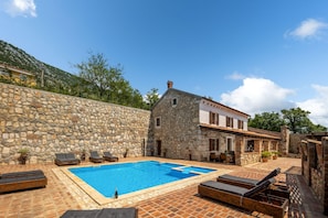 A stone building with a swimming pool, outdoor seating, and a mountainous backdrop. - Pool Villa Cupido in Crikvenica - Drivenik (Vinodol)