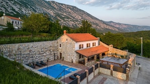A stone house with a swimming pool, outdoor seating, and a mountain backdrop. - Pool Villa Cupido in Crikvenica - Drivenik (Vinodol)
