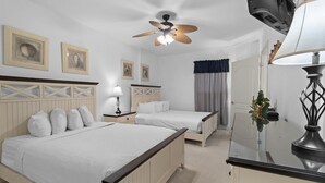 A hotel room with two beds, a ceiling fan, a TV, and a desk with a lamp. - Waves and Relaxation: 2Bdrm Condo with Jetted Tub (North Myrtle Beach)
