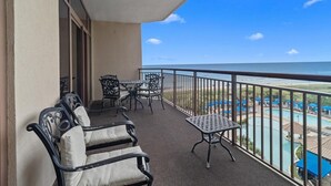 A balcony with outdoor seating, a view of a pool area, and a clear sky. - Beachfront Escape: Oceanview 2 Bedroom Condo (North Myrtle Beach)