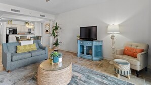 A living room with a sofa, a coffee table, a TV, and a lamp. - Beachfront Escape: Oceanview 2 Bedroom Condo (North Myrtle Beach)