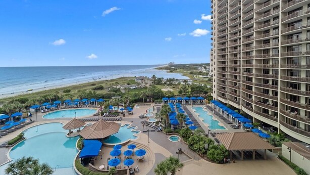 A hotel with multiple swimming pools, a beach view, and a large building with balconies. - Beachfront Escape: Oceanview 2 Bedroom Condo (North Myrtle Beach)