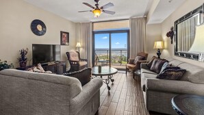 Amplia sala de estar con dos sofás, un televisor y un balcón con vistas.