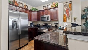 Una cocina moderna con electrodomésticos de acero inoxidable, gabinetes de madera oscura y encimeras de granito.
