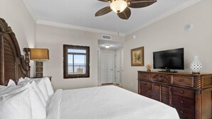 A bedroom with a large bed, a ceiling fan, a television, and a dresser.