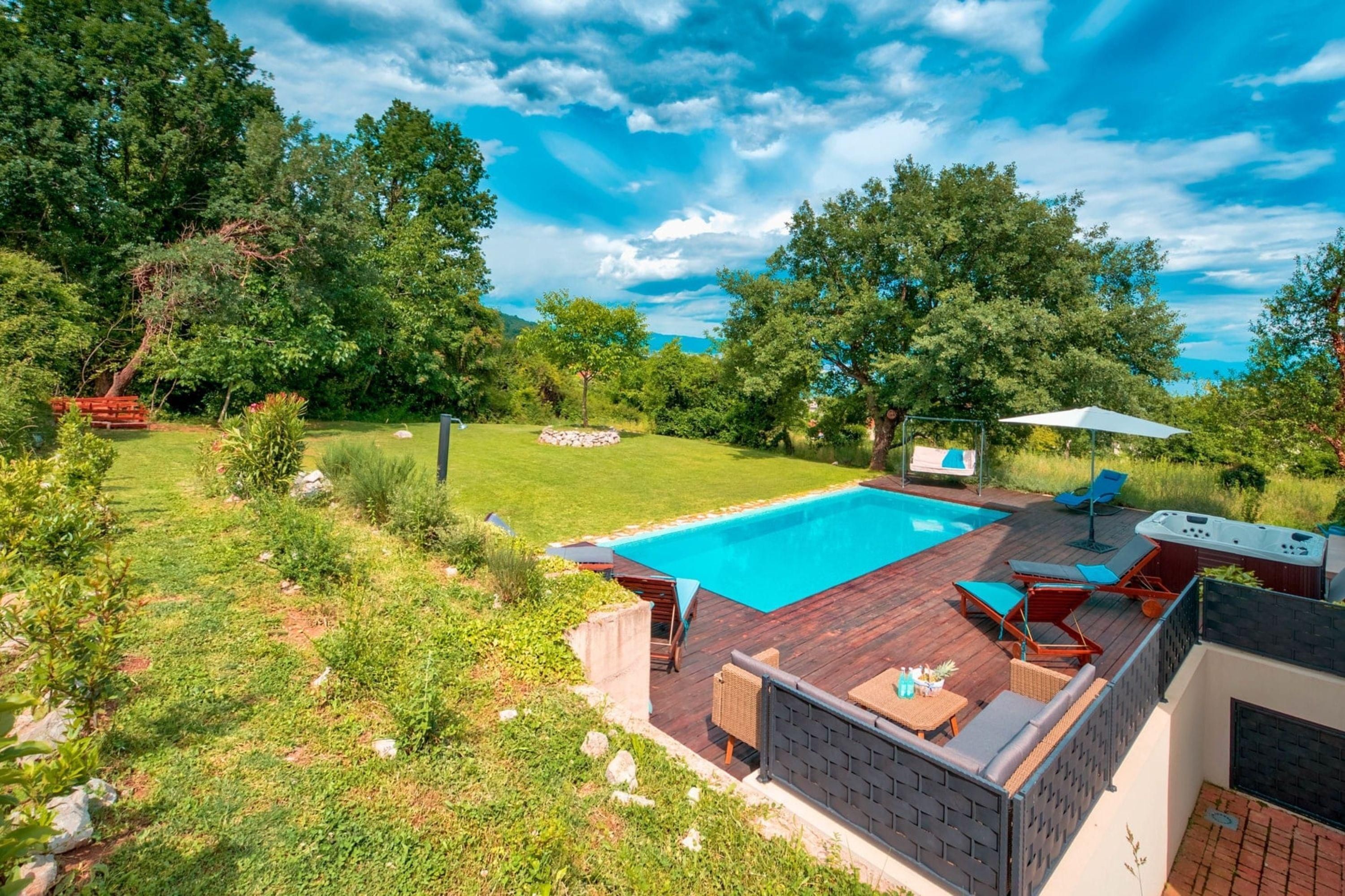 A backyard with a swimming pool, outdoor seating, and a hot tub.