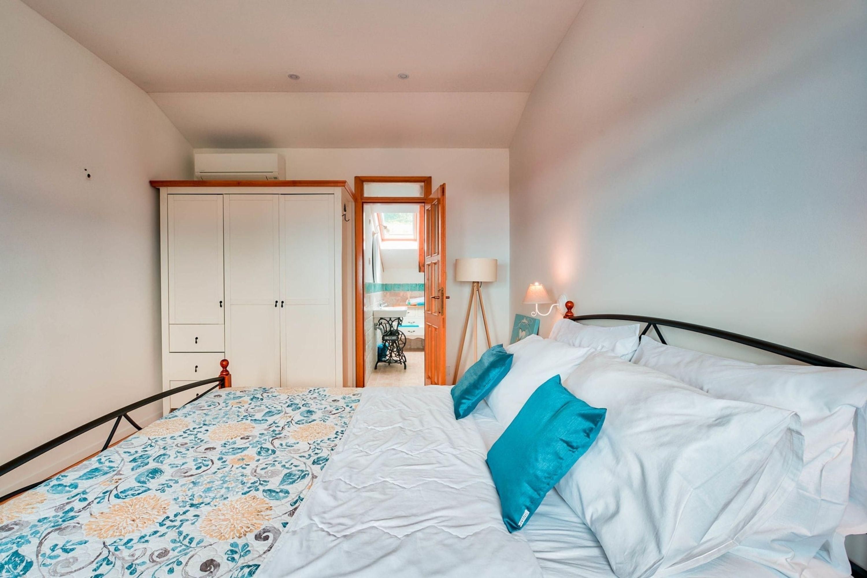 Ein Schlafzimmer mit einem Bett, einem Kleiderschrank und einer Tür zu einem anderen Raum.
