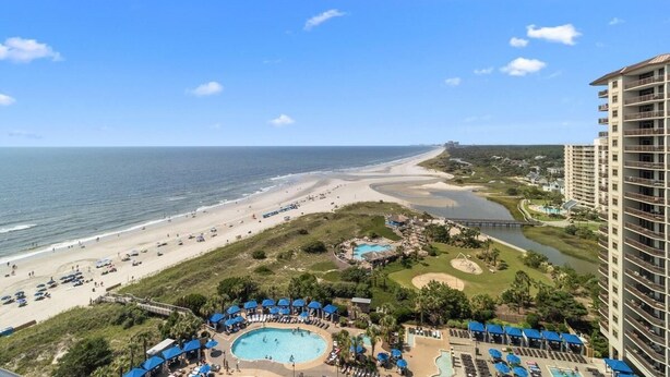 A resort with a large pool, beach access, and a high-rise building.