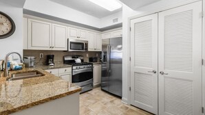 A modern kitchen with white cabinets, stainless steel appliances, and a granite countertop.