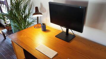 Ein Schreibtisch aus Holz mit einem Computermonitor, einer Tastatur und einer Maus.