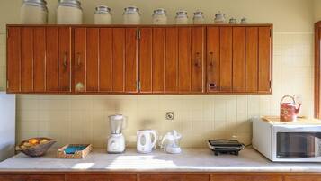 A kitchen with wooden cabinets, a blender, a kettle, a toaster, and a microwave.