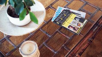 A magazine on a woven table, a potted plant, and a candle.