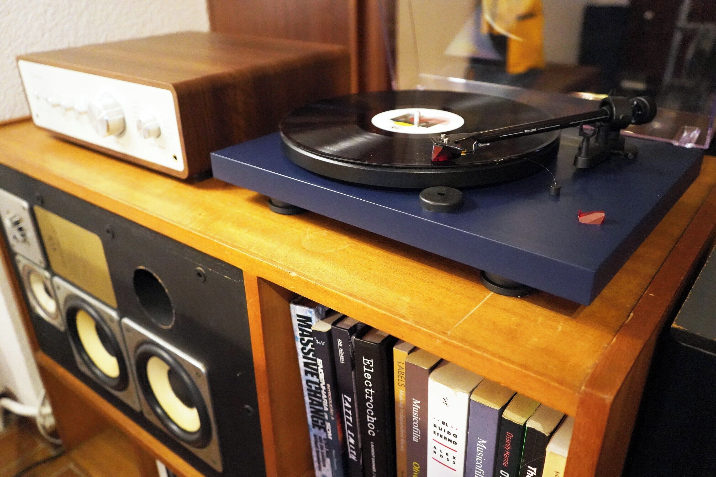 A turntable on a wooden table with a record player and a bookshelf below.