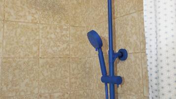 A shower with a blue handheld showerhead and a wall-mounted faucet.