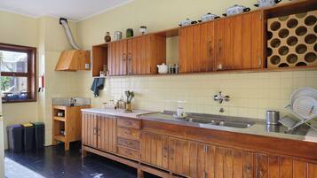 A kitchen with wooden cabinets, a large island with a sink, and a window with blinds.
