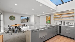 Een moderne keuken met een centraal eiland, grijze keukenkastjes en een dakraam.