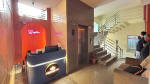 A hotel reception area with a neon sign, a reception desk, a staircase, and a seating area. - Sumitel Premier Inn (Siliguri)