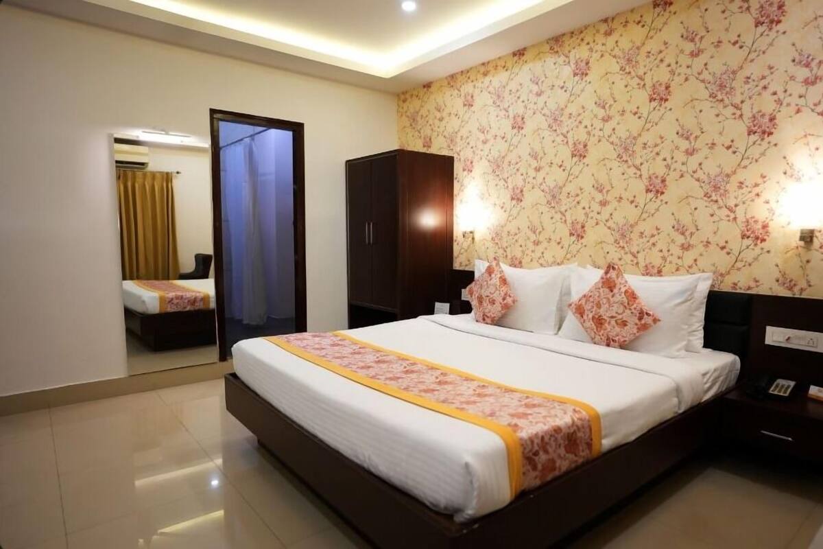 Una habitación de hotel con una cama grande, un armario, una mesita de noche y un espejo.