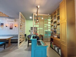 Una habitación acogedora con un escritorio de madera, una silla azul y una estantería llena de libros y botellas.