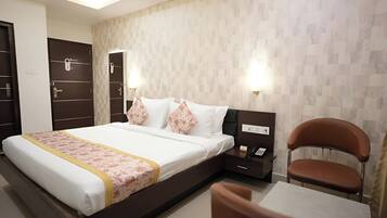 Habitación de hotel con cama, mesita de noche, silla y una pared con diseño decorativo.