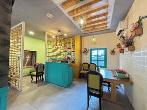 A dining area with a teal-colored counter, wooden chairs, and a table. There are hanging lights and a window with a view. - Sumitel Premier Inn (Siliguri)